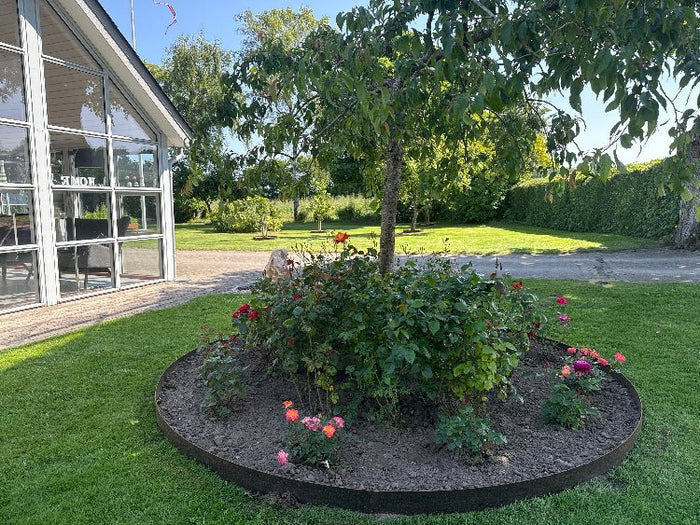 Runde Beeteinfassung aus Cortenstahl um Baum und Rosen im Garten
