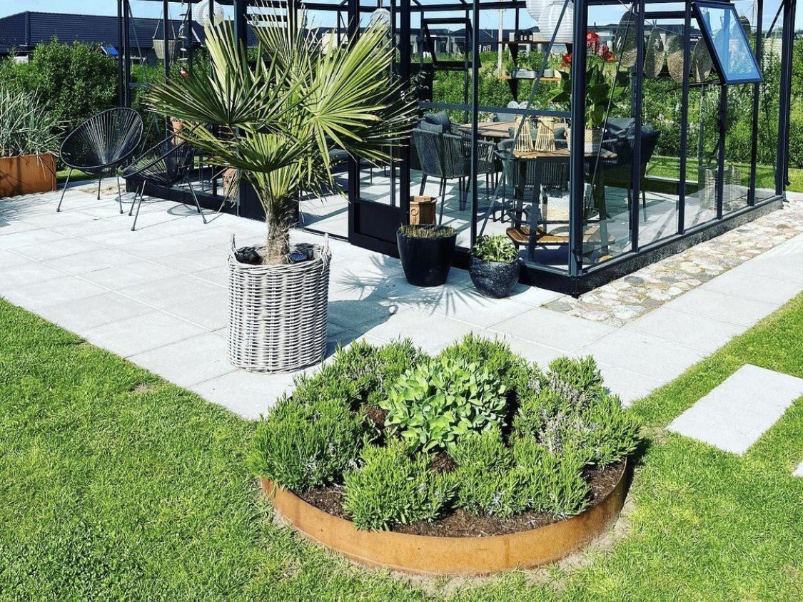 Runde Beetumrandung aus Cortenstahl im modernen Garten neben Terrasse und Gewächshaus – langlebige Beeteinfassung mit natürlicher Rostpatina