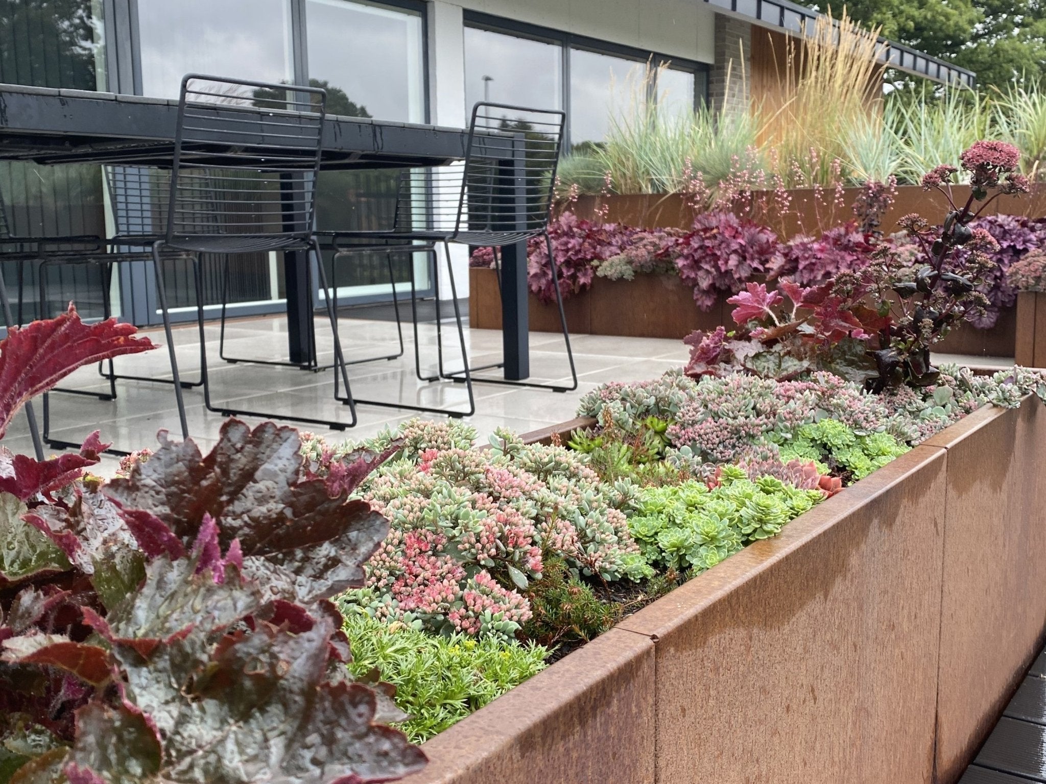 Mehrere Cortenstahl Hochbeete von byJEMA auf moderner Terrasse – stilvolle Gartengestaltung mit Stauden und Gräsern
