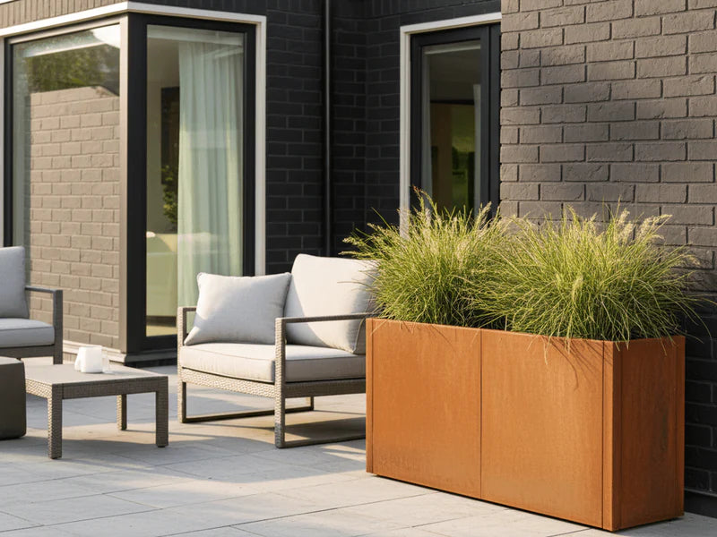CUBY Pflanzkasten aus Cortenstahl mit Gräsern neben Sitzgruppe auf Terrasse