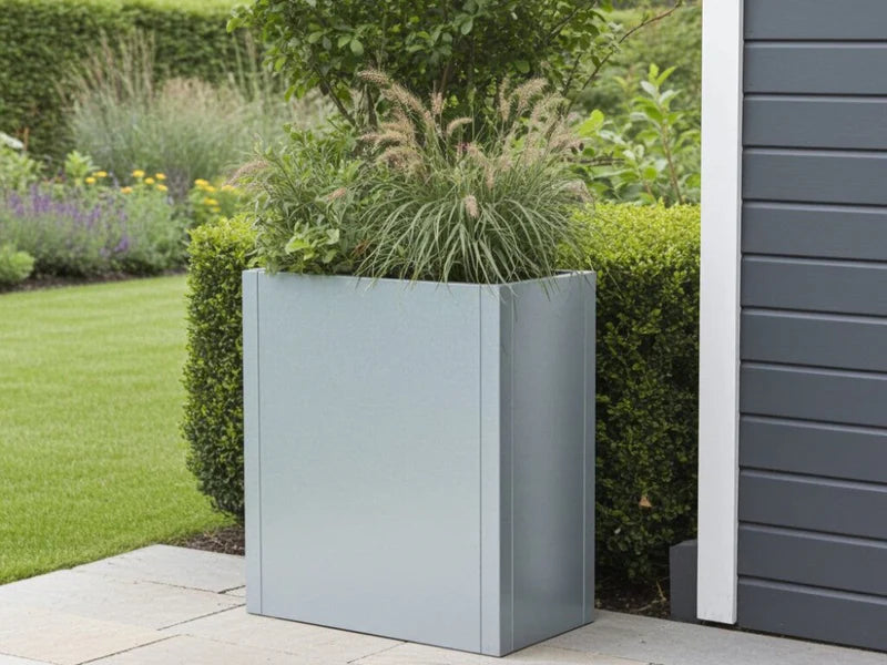 CUBY hoher Pflanzkübel aus verzinktem Stahl mit Ziergräsern an moderner Fassade