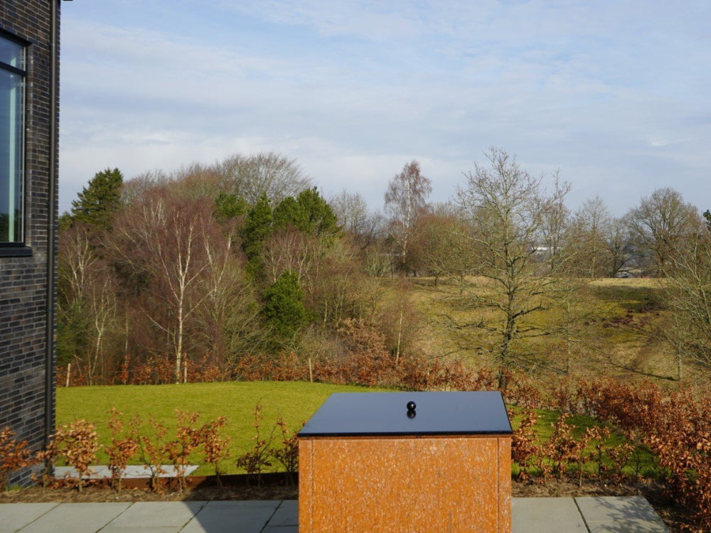 Deckel für Feuergrill aus schwarzem Stahl im Garten mit freiem Ausblick