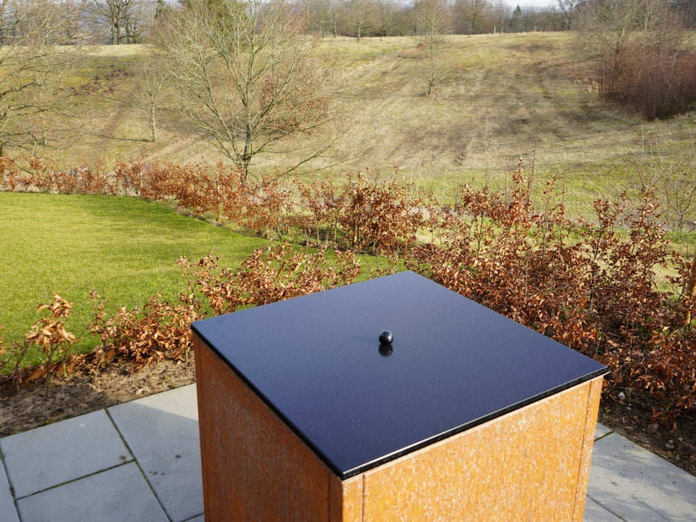 Feuergrill mit Deckel aus schwarzem Stahl in ruhiger Terrassenumgebung