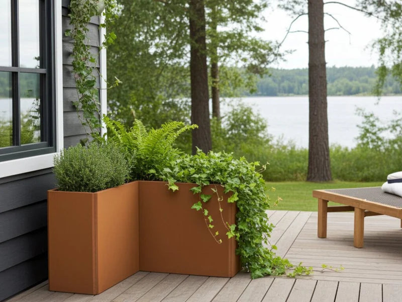 Hoher EDGY Winkel-Pflanzkübel aus Cortenstahl mit grüner Bepflanzung auf Holzterrasse