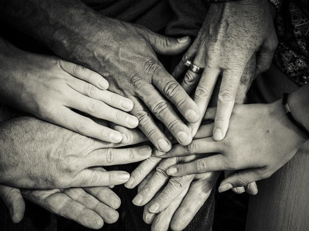 Several hands placed together symbolizing family values, teamwork, unity, and collaboration