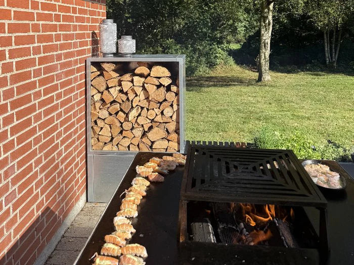 Holzlager aus verzinktem Stahl neben Feuerstelle und Outdoor-Kochbereich