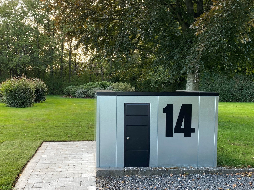 Mülltonnenverkleidung aus Stahl mit Hausnummer vor dem Haus
