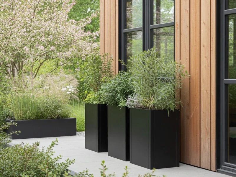Hohe Pflanzkästen aus schwarzem Stahl an moderner Holzfassade