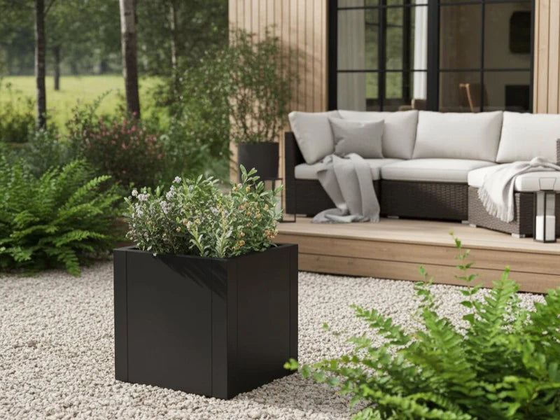 Pflanzkasten aus schwarzem Stahl mit grüner Bepflanzung neben Loungebereich