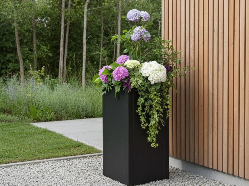 Hoher Pflanzkübel aus schwarzem Stahl mit Hortensien