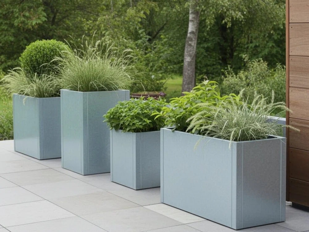 Hoher Pflanzkübel aus verzinktem Stahl mit Ziergräsern auf moderner Terrasse