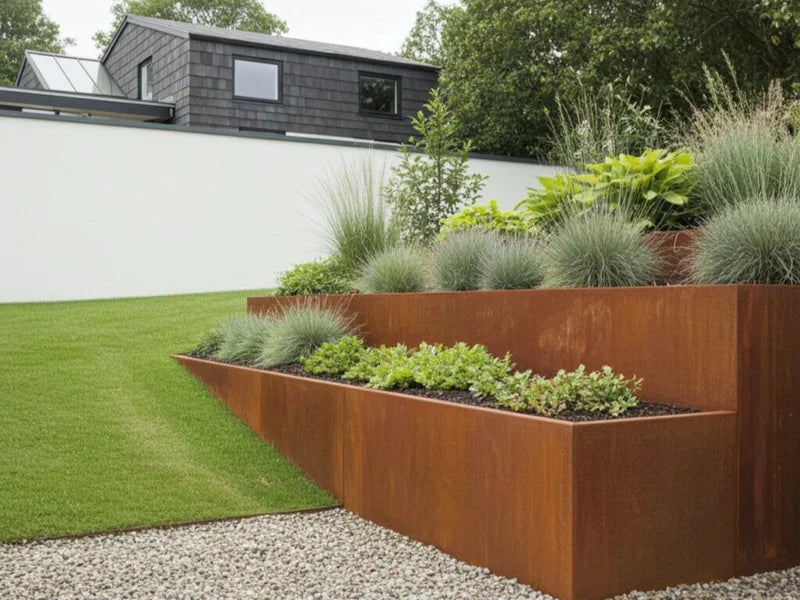 Terrassierte Stützmauer aus Cortenstahl mit Ziergräsern im Garten
