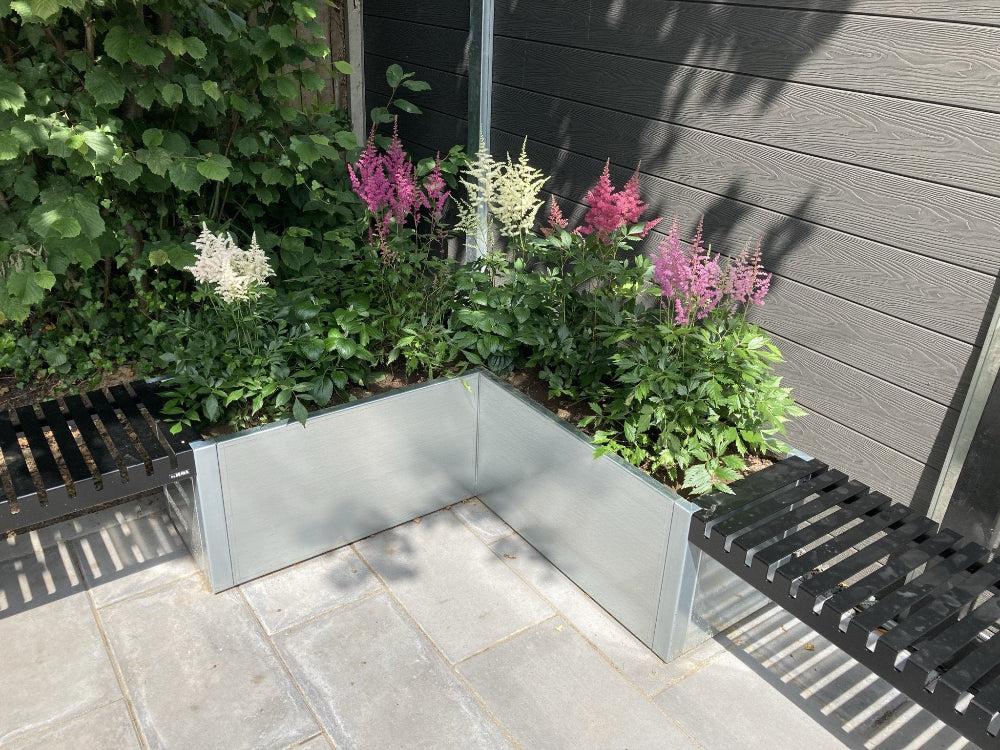 Winkel Pflanzkasten aus verzinktem Stahl mit blühenden Pflanzen im Garten