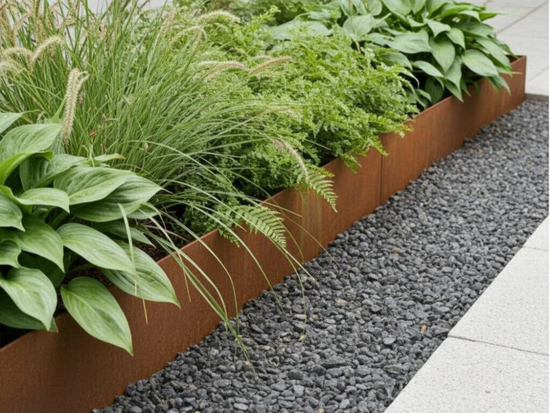 Beeteinfassung aus Cortenstahl mit Pflanzen entlang eines Kieswegs