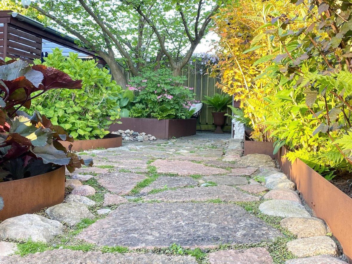 Geschwungene Beeteinfassung aus Cortenstahl mit Ziersträuchern – langlebige Gartenlösung in Rostoptik