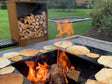 byJEMA Feuerstelle aus Cortenstahl mit Grillplatte – Pfannkuchen werden über offenem Feuer im Garten zubereitet