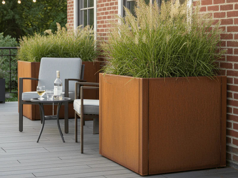 CUBY Pflanzkasten aus Cortenstahl mit Ziergras auf Terrasse bei Backsteinhaus