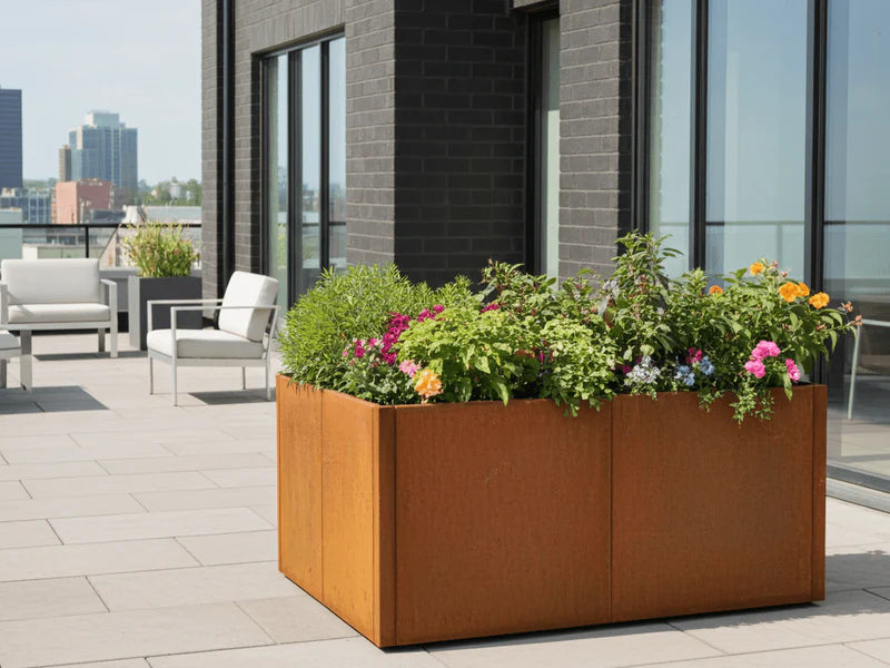 Großer Pflanzkasten aus Cortenstahl von CUBY mit bunten Blumen auf Terrasse