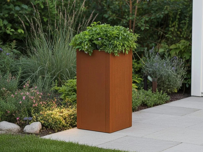 Hoher CUBY Pflanzkasten aus Cortenstahl neben Gartenbeet