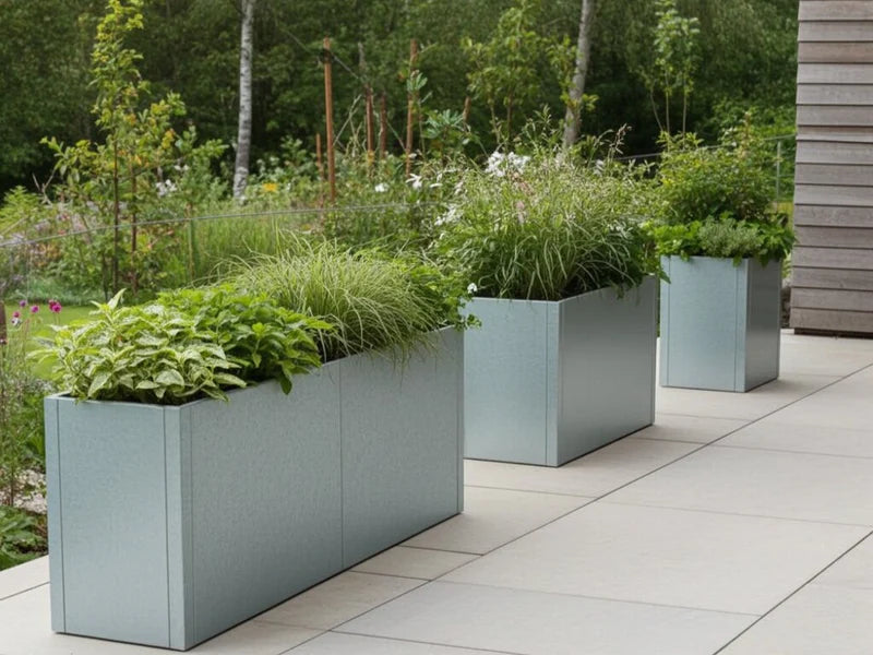 Pflanzkästen aus verzinktem Stahl von CUBY mit Stauden entlang Terrasse