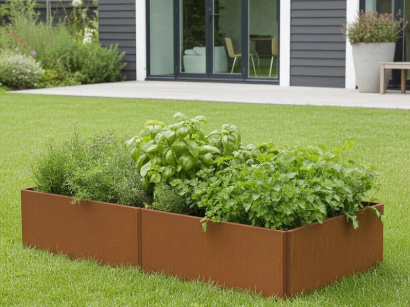 Rechteckiges EDGY Hochbeet aus Cortenstahl mit dichter Bepflanzung vor modernem Haus