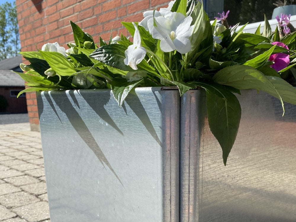 Detail eines EDGY Hochbeets aus verzinktem Stahl mit weißen Blumen