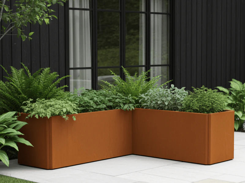 Winkelförmiger EDGY Pflanzkübel aus Cortenstahl an moderner Hausfassade