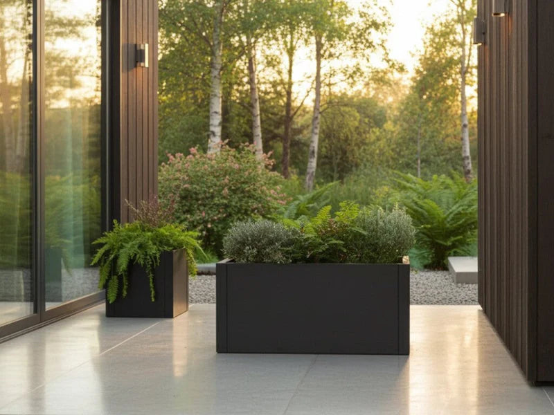 Pflanzkasten aus schwarzem Stahl mit grünen Pflanzen in modernem Gartenbereich