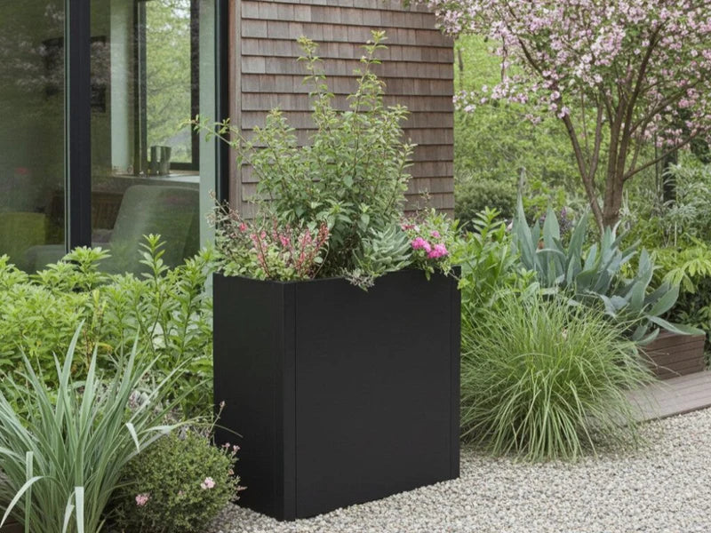 Pflanzkasten aus schwarzem Stahl mit grüner Bepflanzung im Garten