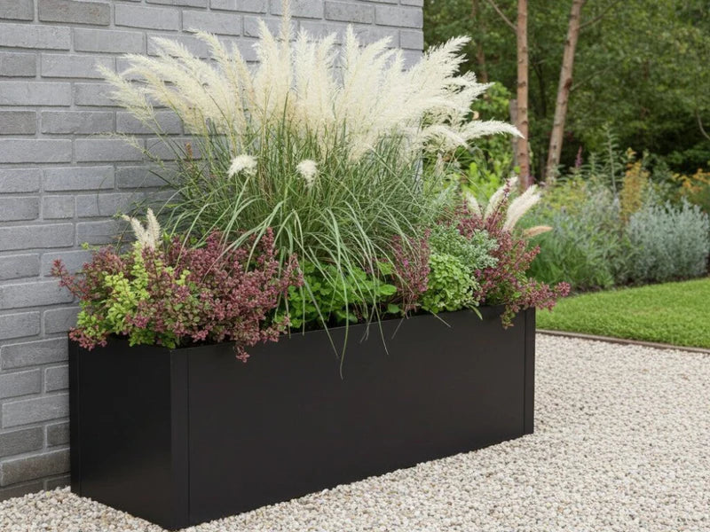 Pflanzkasten aus schwarzem Stahl mit Ziergräsern im Kiesgarten