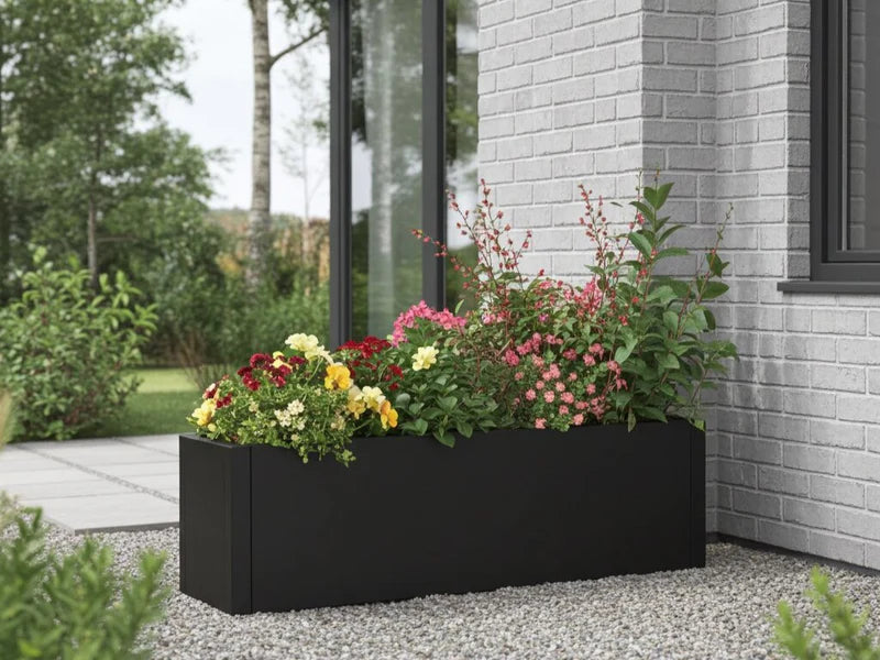 Pflanzkasten aus schwarzem Stahl mit Stauden und Blüten vor Hausfassade
