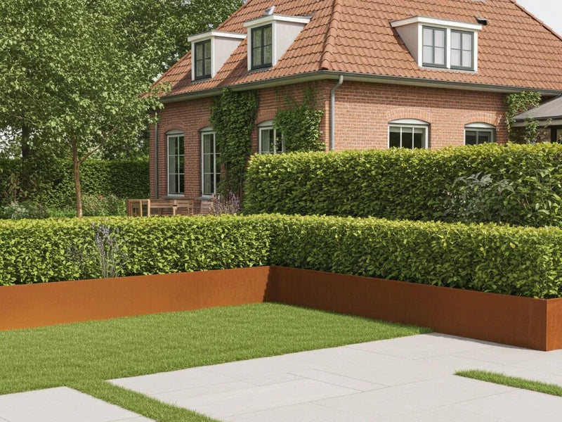 Stützmauer aus Cortenstahl im Gartenbeet neben Haus